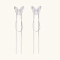 Pair of silver threader earrings with crystal butterfly tops and long chain drops on cream background.